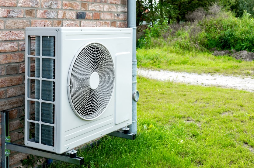 HVAC equipment outside of a home, mounted to a brick wall.