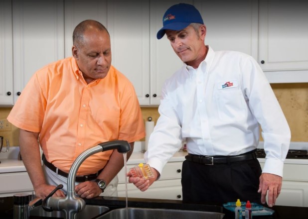 Plumber in Frisco, TX, helping a customer with his kitchen sink at his home.