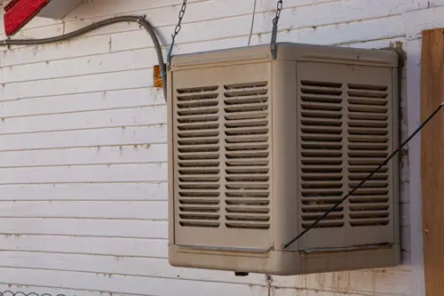 Exterior wall-mounted swamp cooler system installed on a residential building in a dry climate.