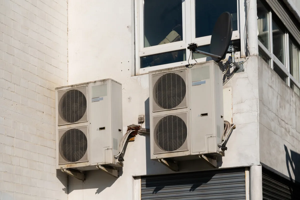 Exterior wall-mounted split-level air conditioning condenser units installed outside a multi-level residential building.