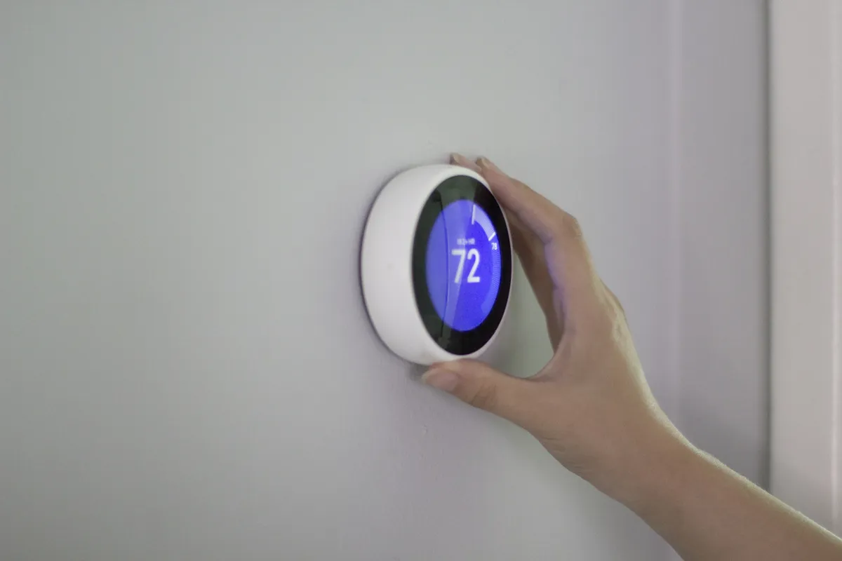 Smart thermostat installation and temperature adjustment on a residential HVAC system wall control panel.