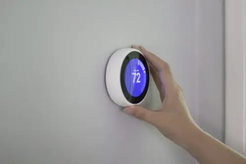 Smart thermostat installation and temperature adjustment on a residential HVAC system wall control panel.